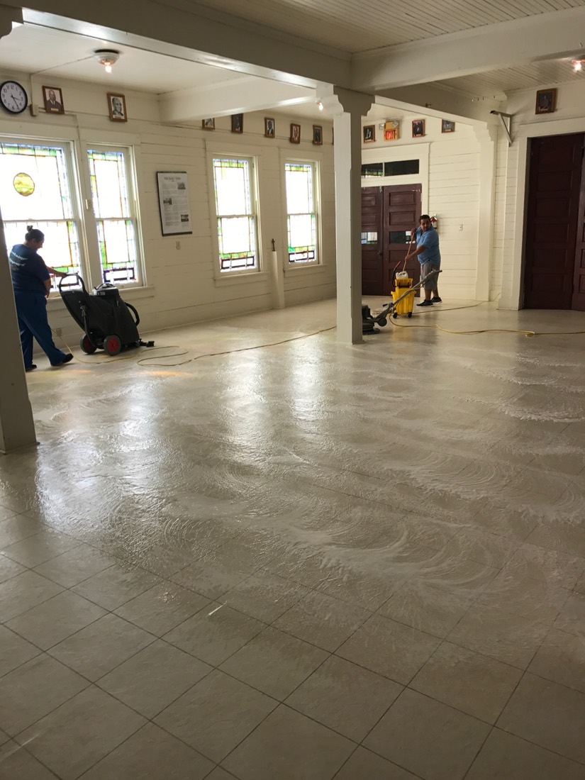 Two Gulfside crew members stripping and refinishing a tile floor
