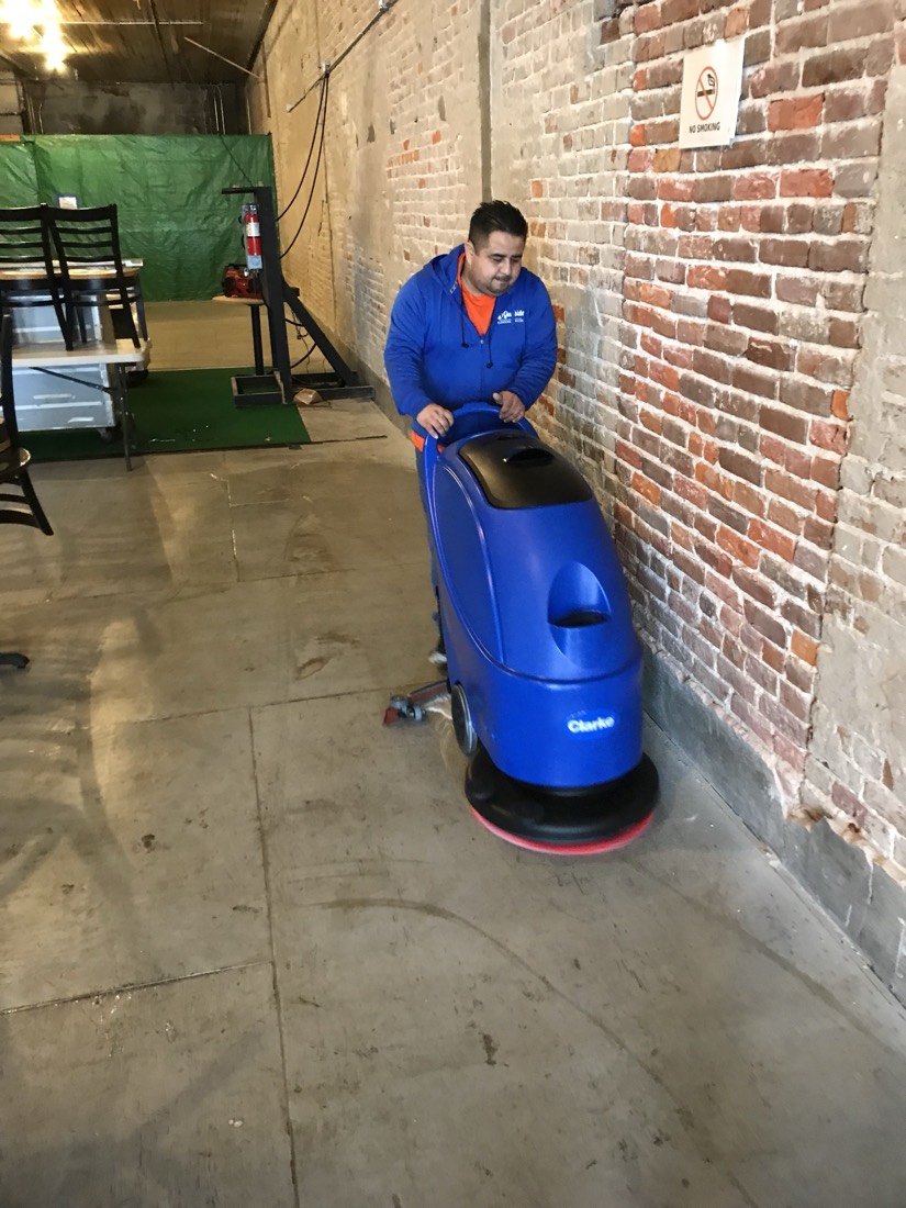 A Gulfside cleaner running a Clarke floor scrubber over a concrete floor